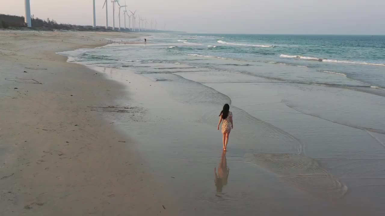 航拍海南文昌海岸沙滩风力发电机少女海滩行走视频素材