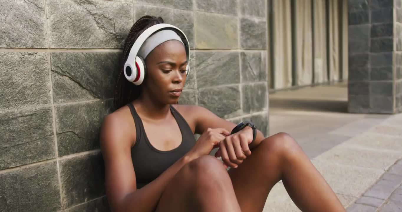 非裔美国妇女在户外运动，戴着无线耳机，戴着智能手表视频素材