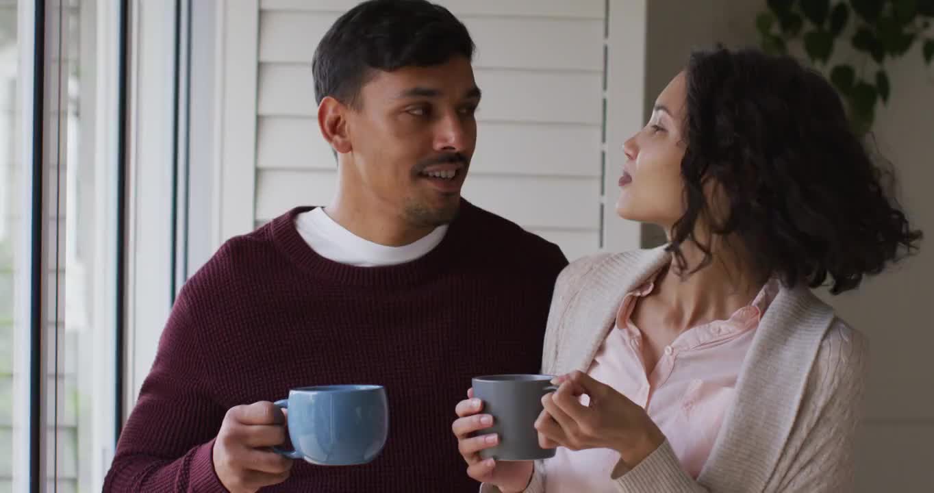 一对浪漫的西班牙夫妇站在窗前，喝着咖啡，拥抱在一起视频素材