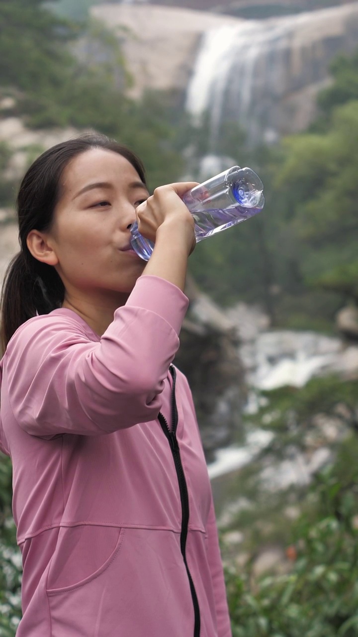亚洲中国人女性在瀑布下喝水饮用水视频素材