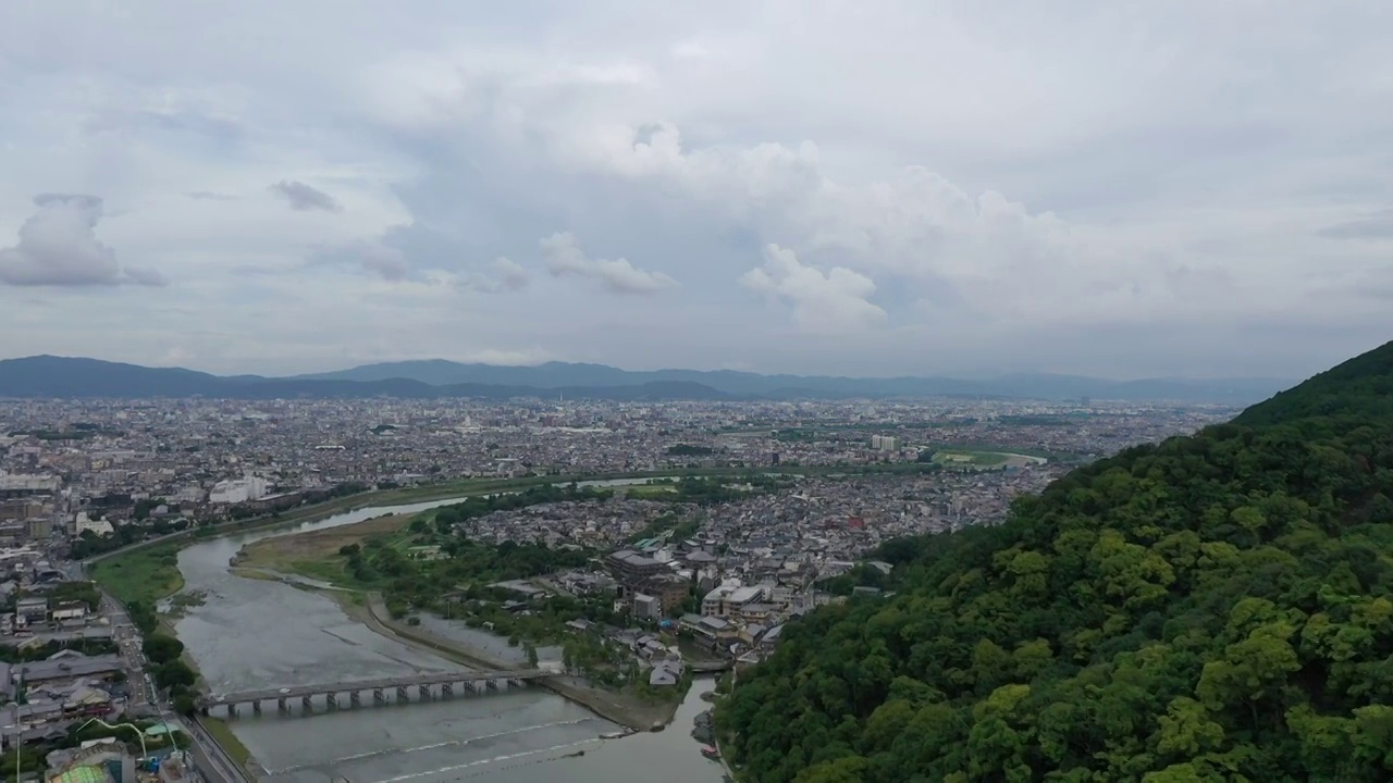 日本京都岚山渡月桥地区山谷河流与城市天际线夏季户外航拍视角视频素材