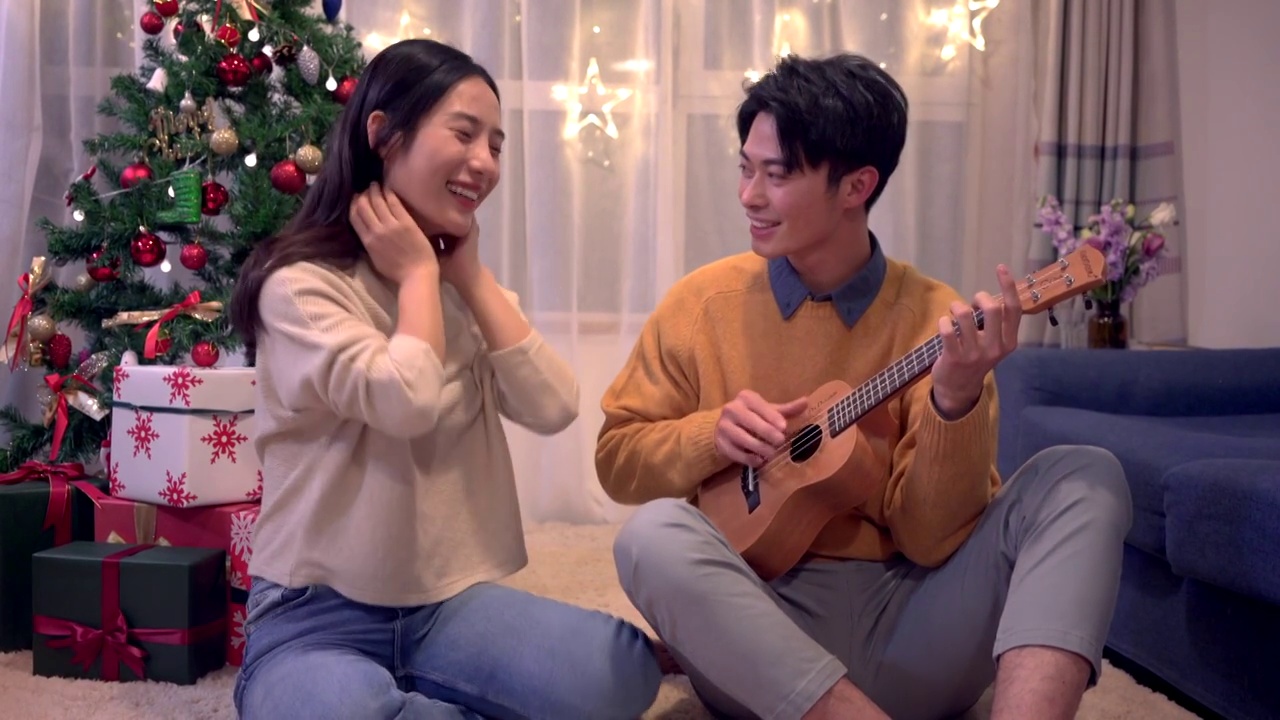 年轻情侣圣诞节在家弹琴唱歌视频素材