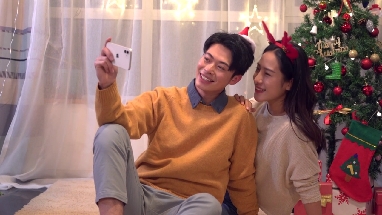 年轻情侣圣诞节在家使用手机自拍视频素材
