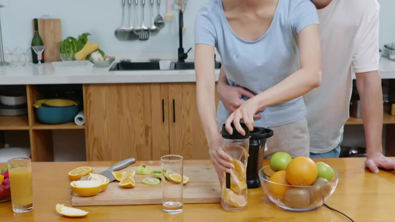 快乐的年轻夫妇在厨房榨果汁视频素材