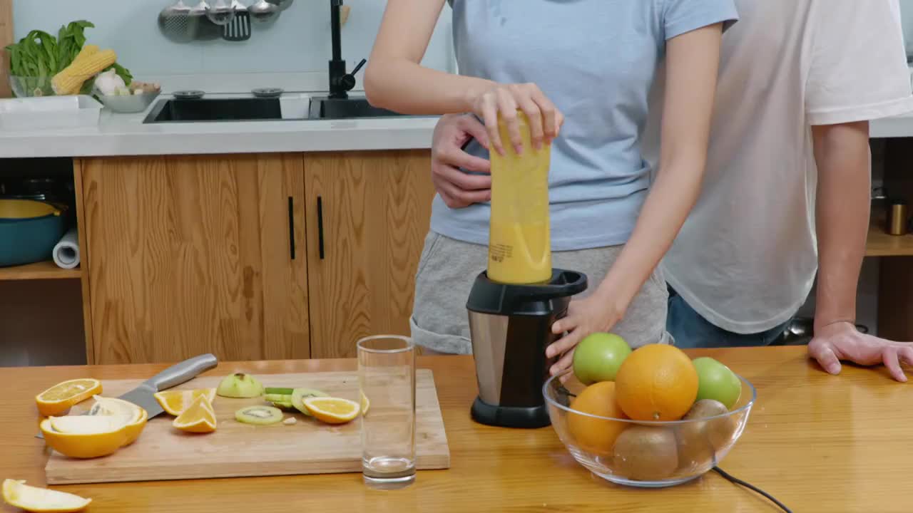 快乐的年轻夫妇在厨房榨果汁视频素材