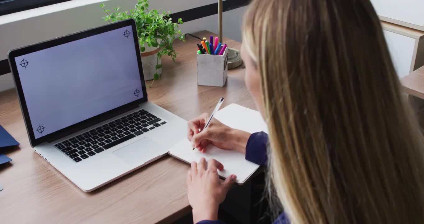 白人女商人在视频通话中做笔记，使用笔记本电脑，屏幕上有拷贝空间视频下载