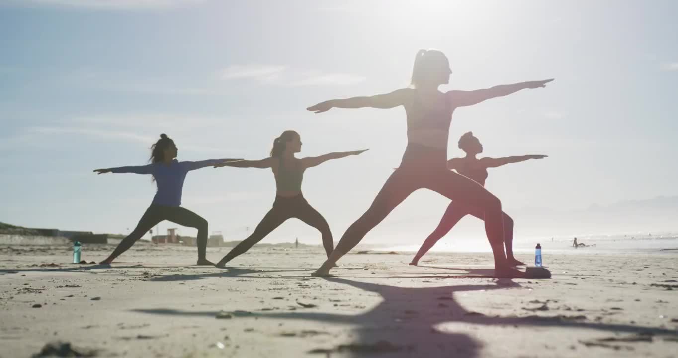 一群不同类型的女性朋友在沙滩上练习瑜伽视频下载