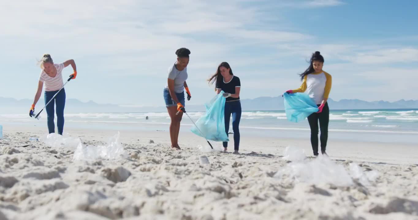 一群女性朋友在海滩上用垃圾袋扔垃圾视频素材