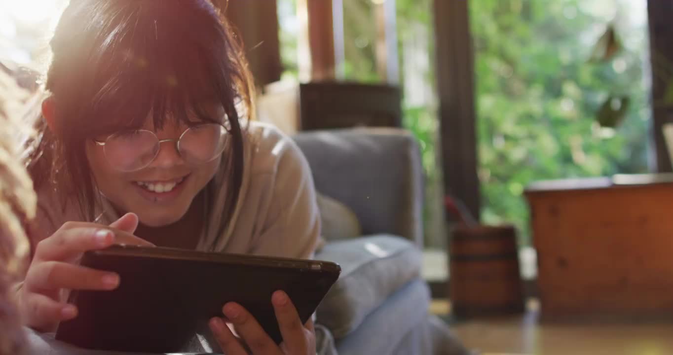 亚洲女孩躺在沙发上和使用平板电脑微笑视频下载