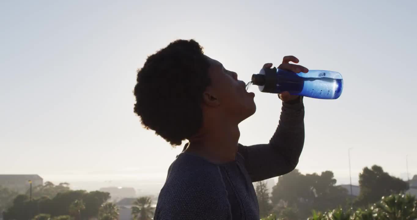 健康的非裔美国人在城市户外运动，休息，喝瓶装水视频素材