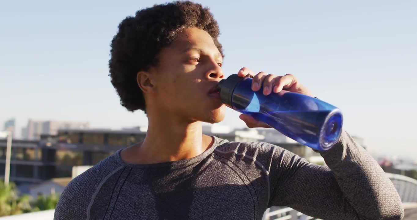 健康的非裔美国人在城市户外运动，休息，在阳光下喝瓶装水视频素材