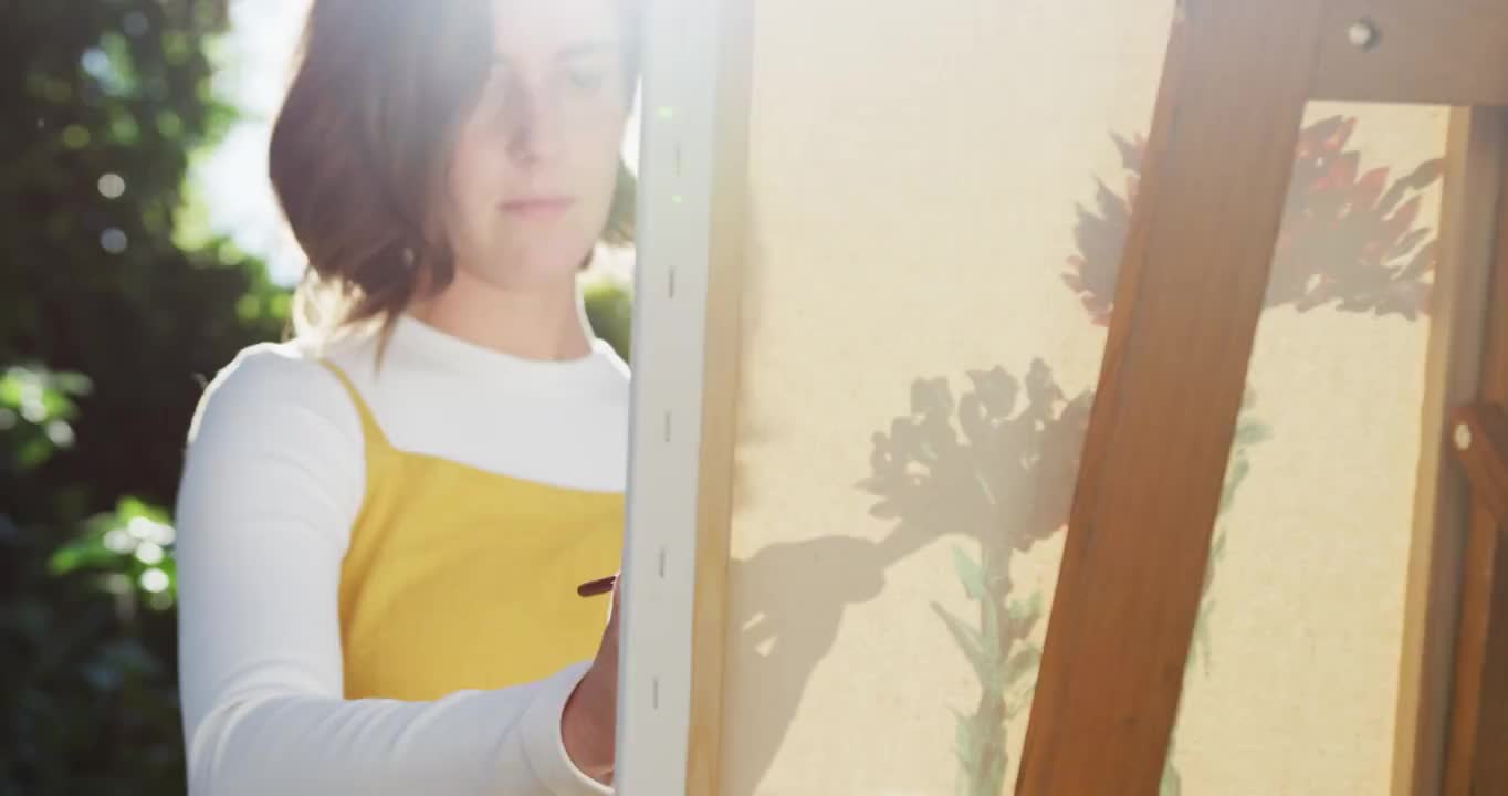一个棕色头发的白人女人在阳光花园画画视频下载