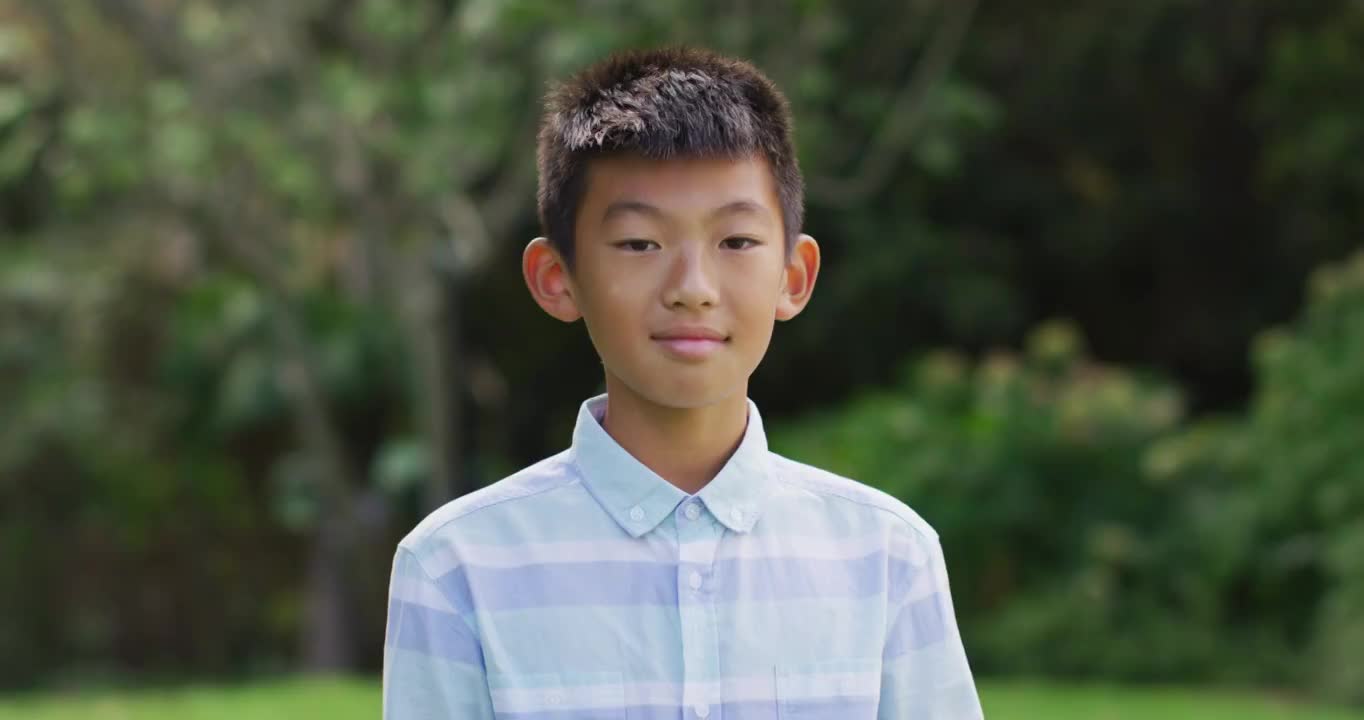 快乐的亚洲男孩的肖像看着照相机微笑和大笑在花园视频素材