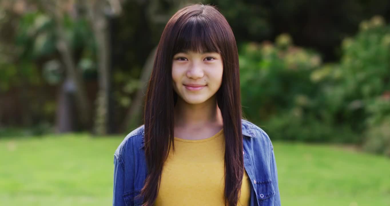 快乐的亚洲少女的肖像看着照相机微笑和大笑在花园视频下载