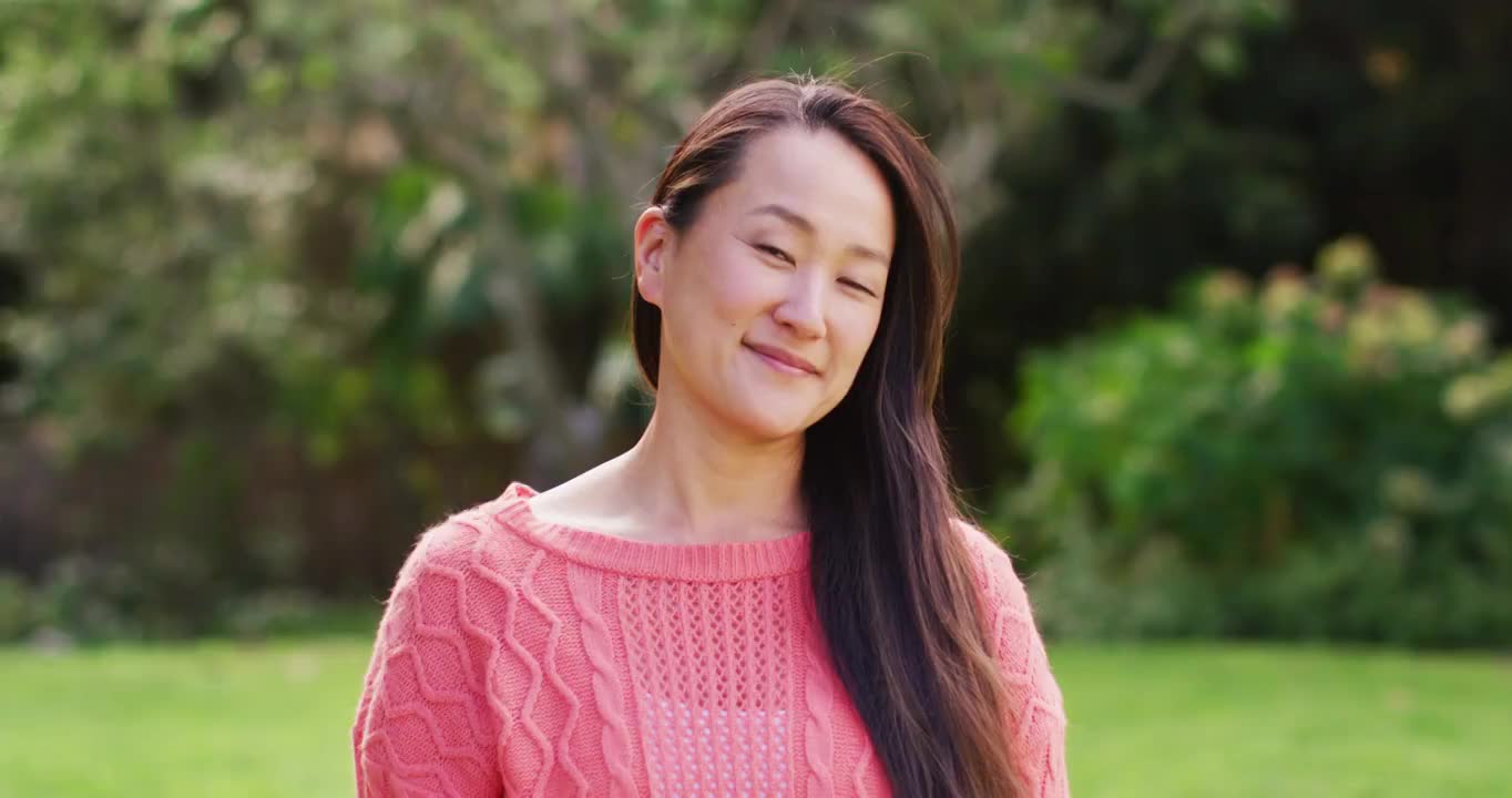 快乐的亚洲妇女的肖像看着照相机微笑和大笑在花园视频素材