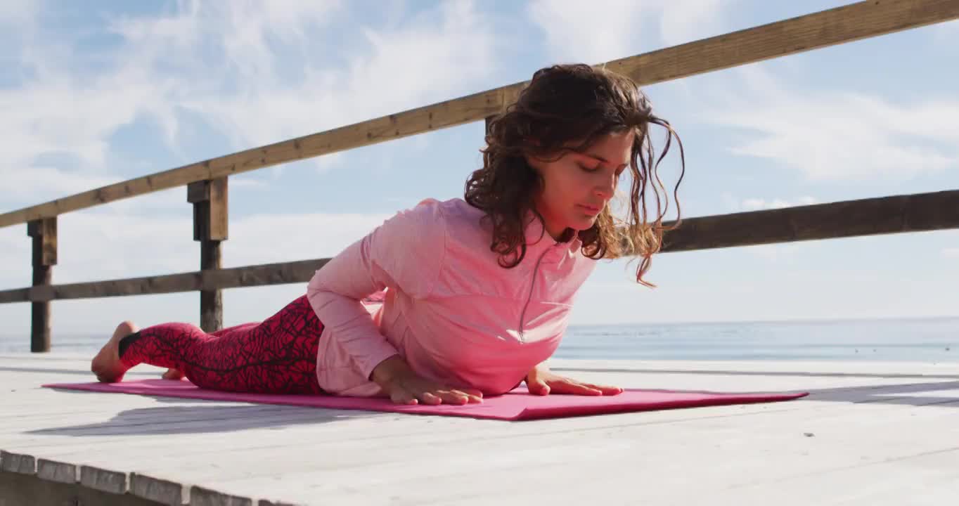 健康的混血女子在户外练习瑜伽，躺在海边，眼睛闭着视频购买
