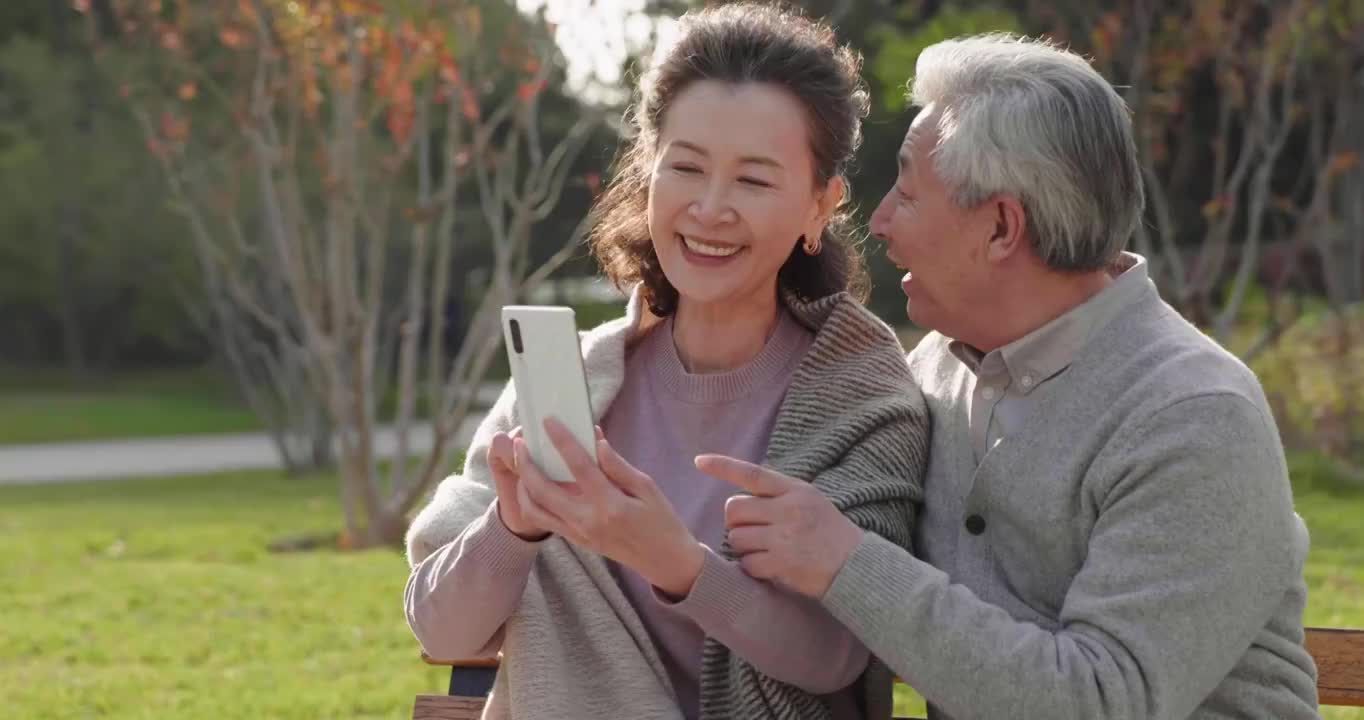 老年夫妇在公园使用手机视频下载