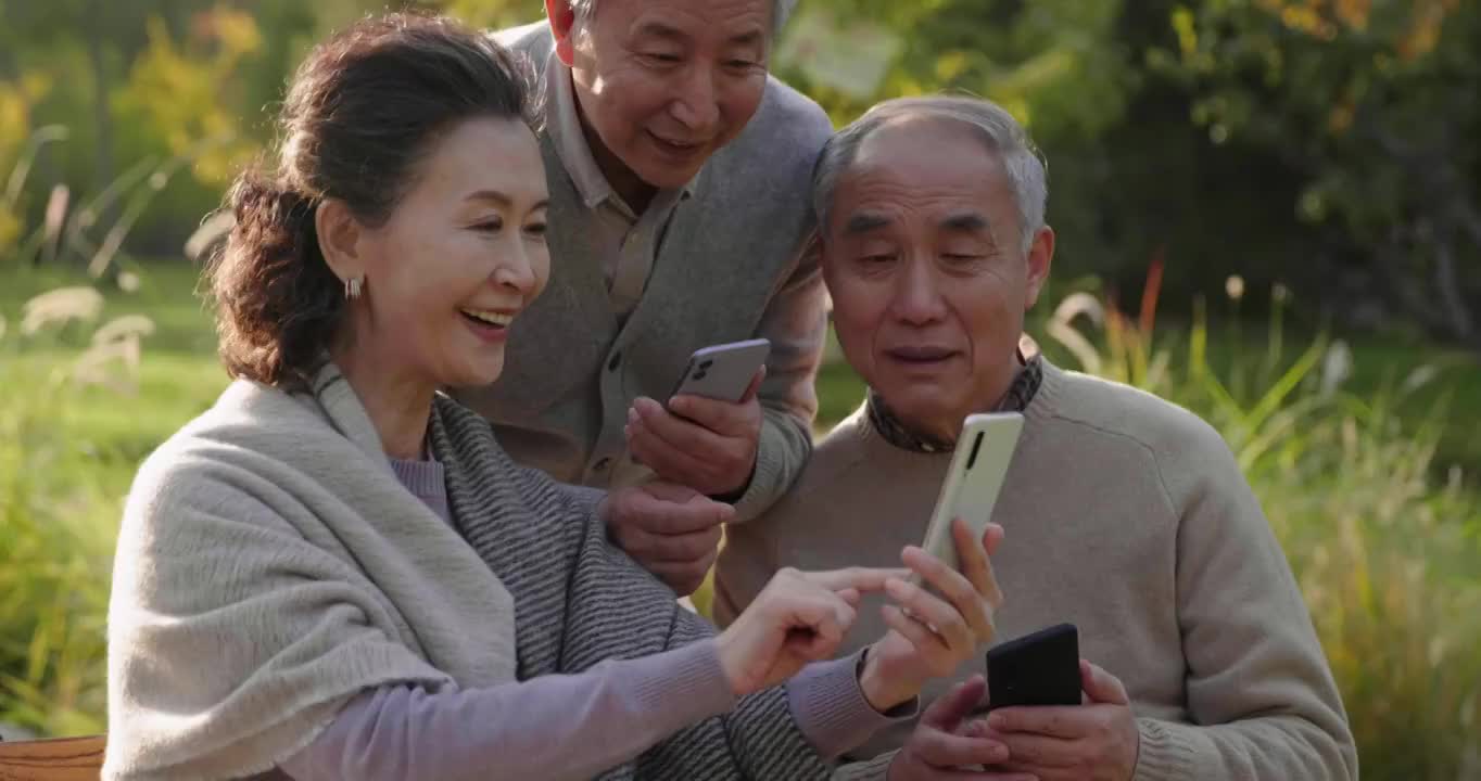 老年人在公园使用手机视频下载