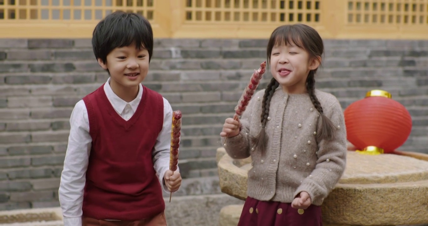 快乐的兄妹俩在院子里吃糖葫芦视频素材