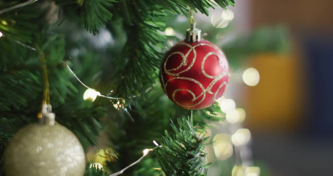 在模糊的背景上用小玩意和仙女灯装饰的圣诞树的视频视频下载