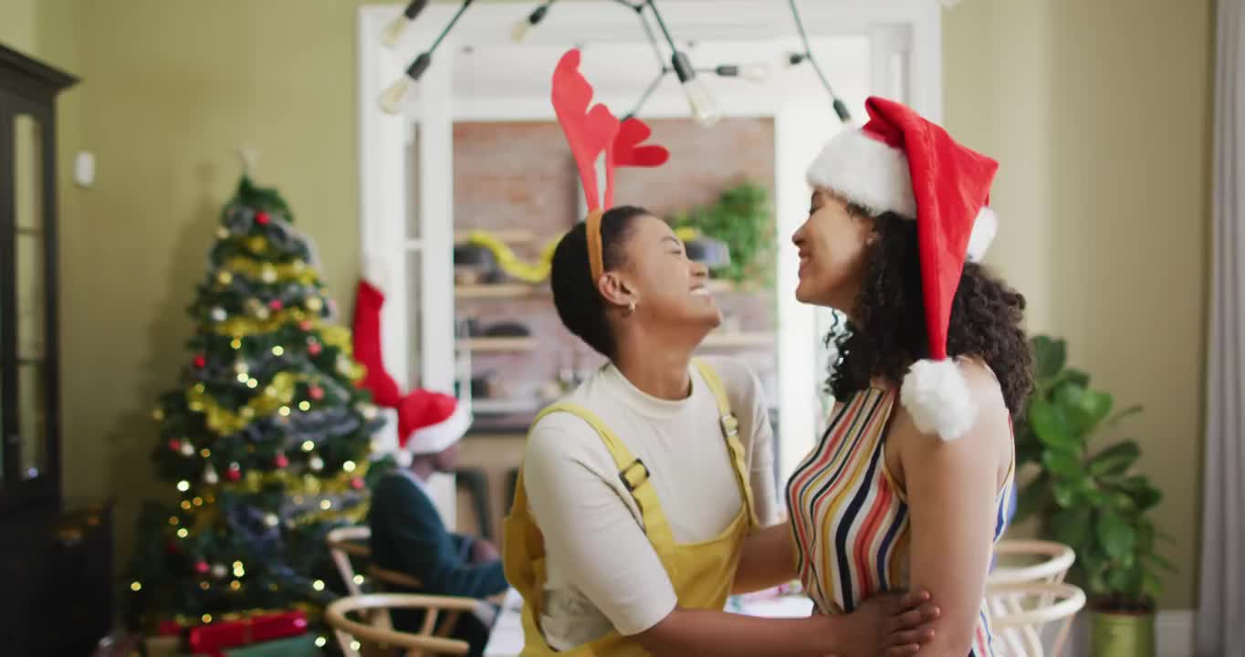 两个快乐多样的女性朋友在圣诞节期间戴着圣诞帽拍照视频下载