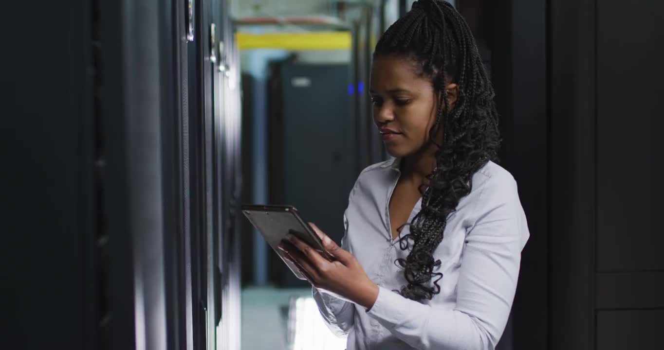 非裔美国女性计算机技术人员使用平板电脑在企业服务器室工作视频素材