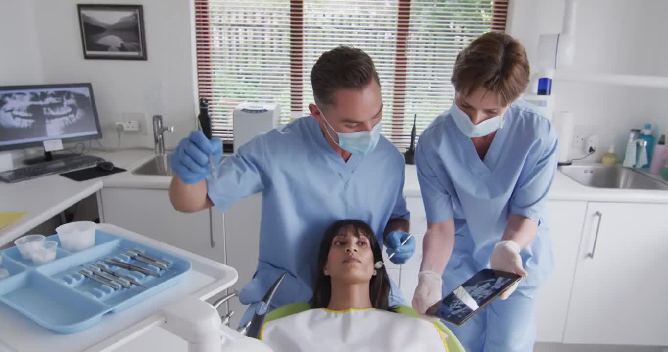 在现代牙科诊所，白人男性牙医带着口罩为女性病人检查牙齿视频下载