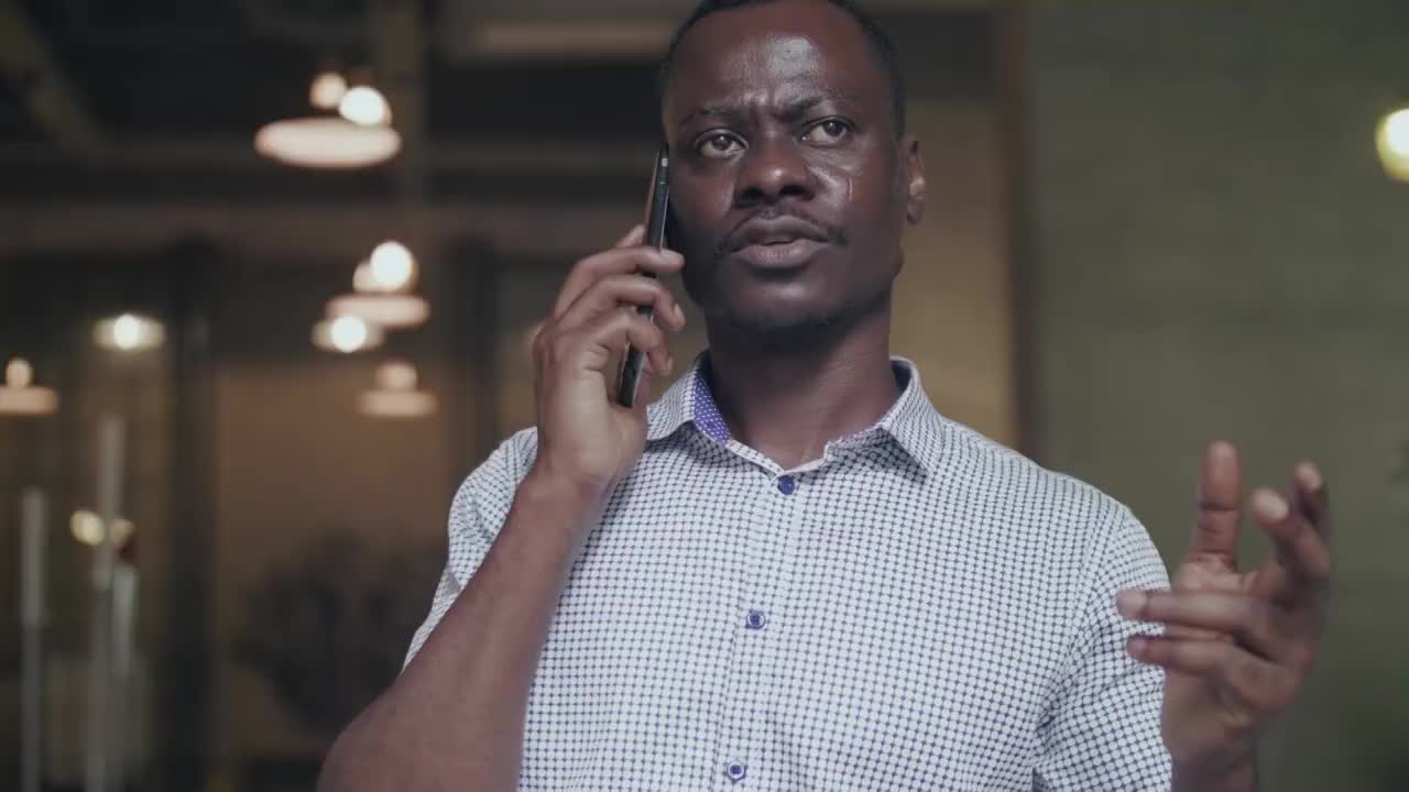 一位非洲黑人商人站在窗前喝咖啡，用手机交谈视频素材