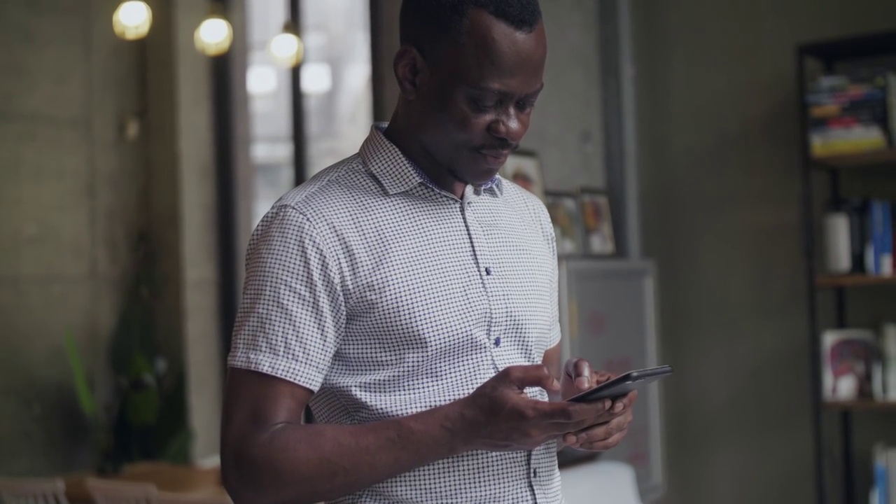一位非洲黑人商人站在窗前喝咖啡，用手机交谈视频素材