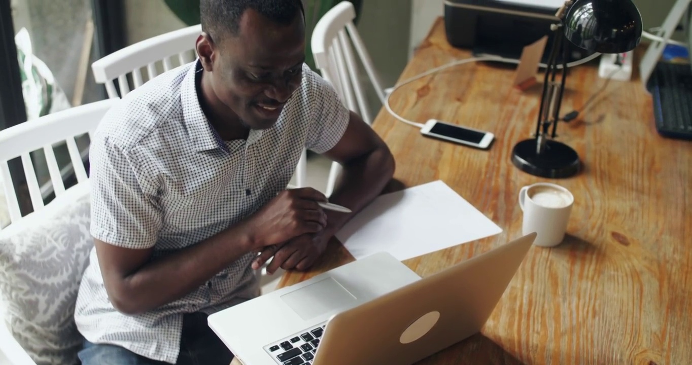 快乐非洲男人视频聊天室的俯视图黑人在室内使用笔记本电脑工作人视频素材
