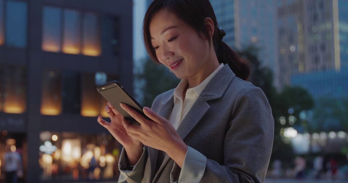 一位职业女性正在微笑着浏览她的手机。视频素材