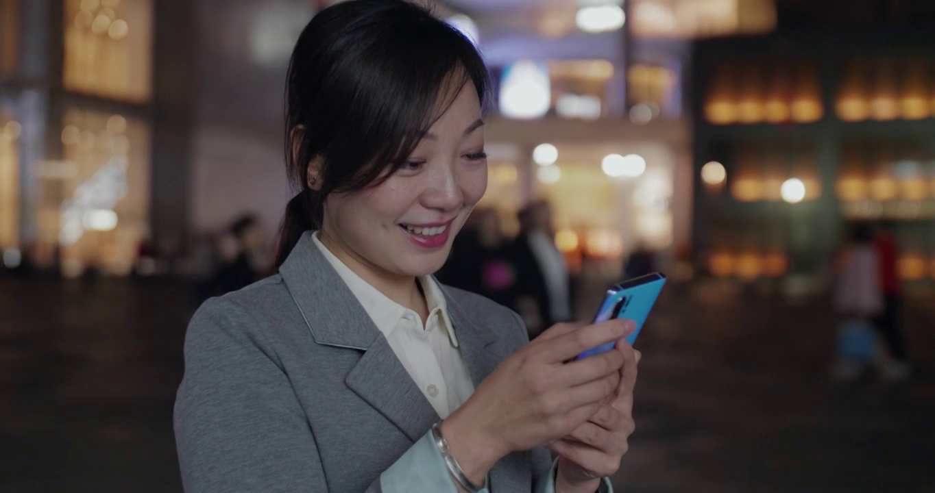 一位职业女性正在微笑着浏览她的手机。视频素材