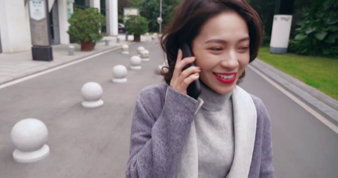 前景色美丽的亚洲女子在手机上与朋友聊天漫步在城市道路上快乐的视频素材