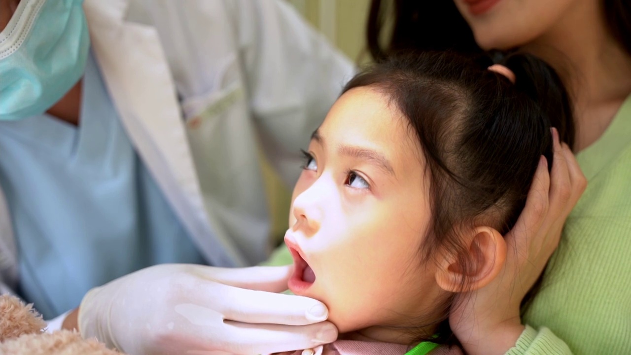 妈妈抱着小孩牙科医生在治疗视频下载