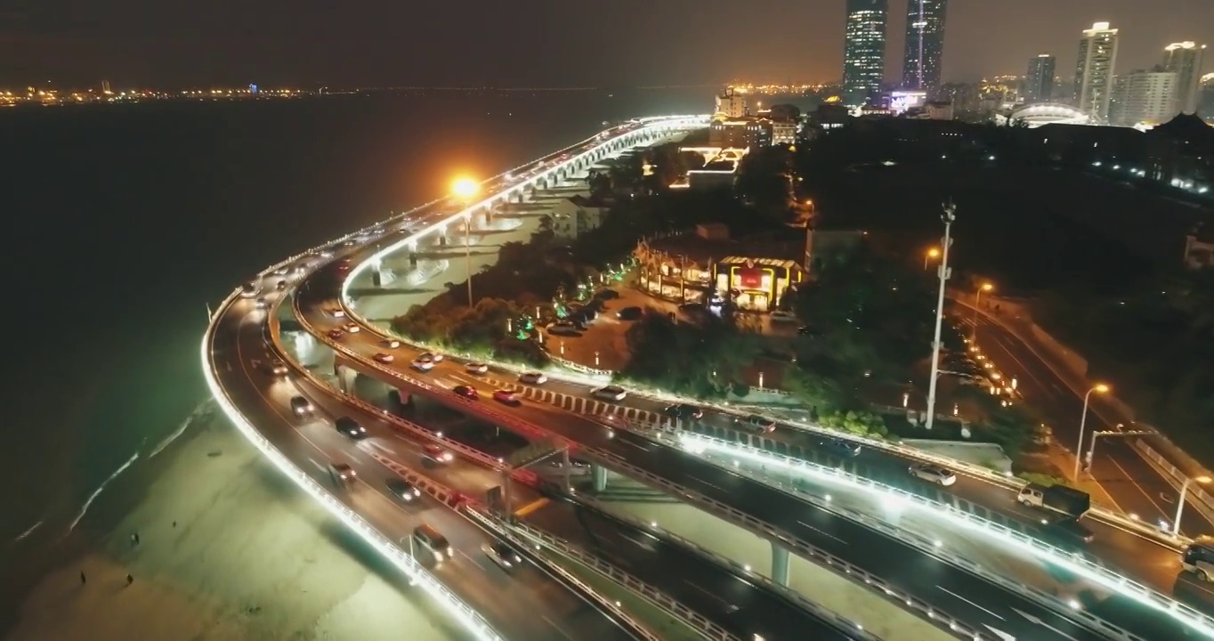 无人机拍摄了中国福建厦门市海边的交通和建筑物，夜间行驶的车辆和灯光明亮的建筑物视频下载
