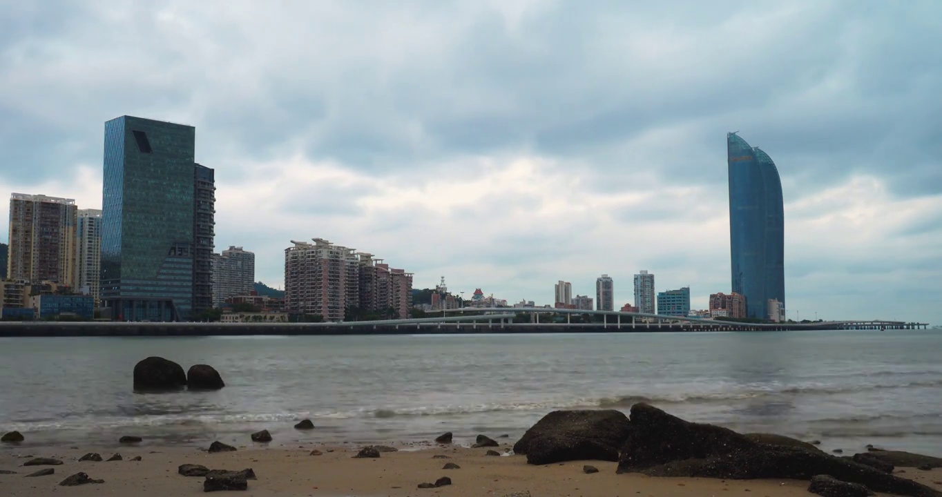 中国福建厦门的早晨，海浪在海滩上轻轻拍打，云朵飘过高楼大厦视频素材