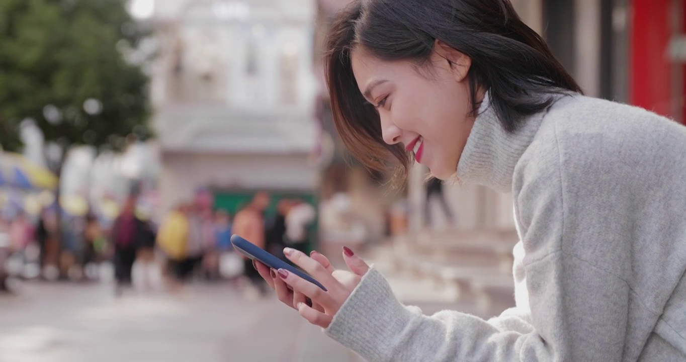 亚洲妇女在街上使用手机视频素材