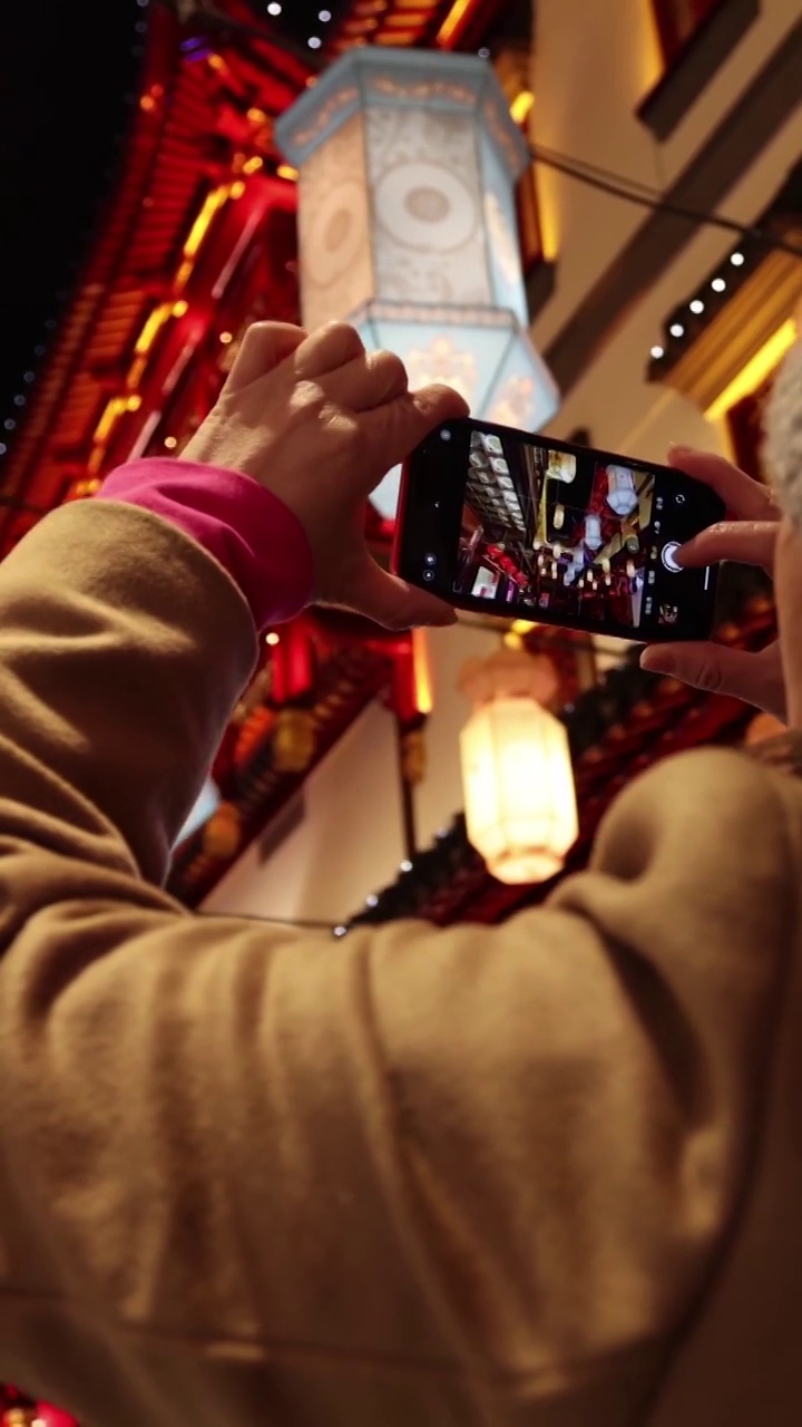 夜晚在上海豫园用手机拍照的女人背影视频素材