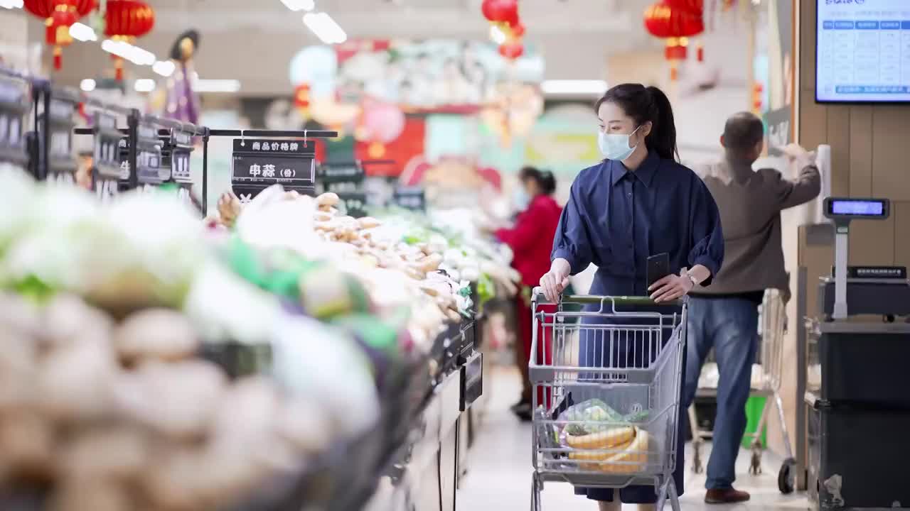 年轻女子在超市里推着购物车购买蔬菜视频素材