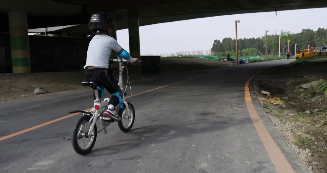 骑行运动：小男孩在天府绿道上骑自行车视频下载
