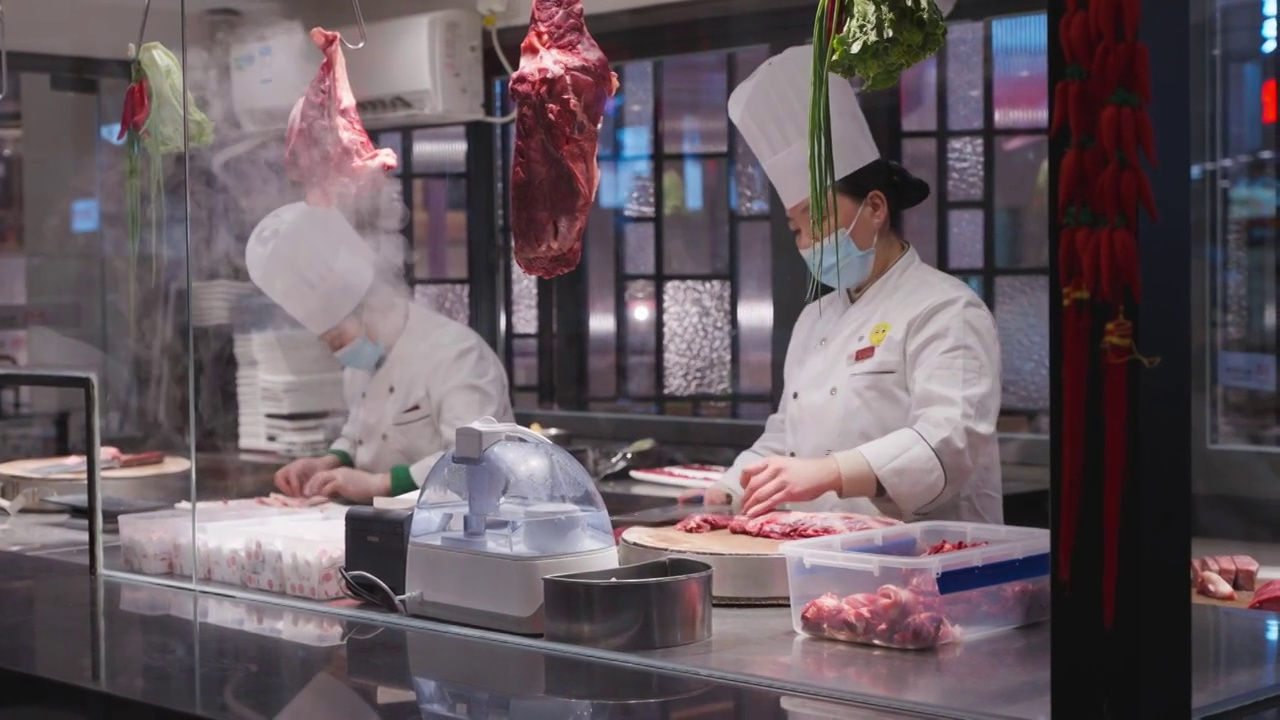 成都饭店里两位穿着工作服的厨师在厨房切牛肉准备火锅食材视频素材