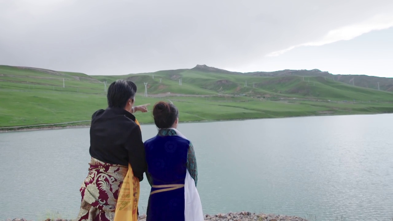 穿着藏族服饰的工作人员眺望湖面视频下载
