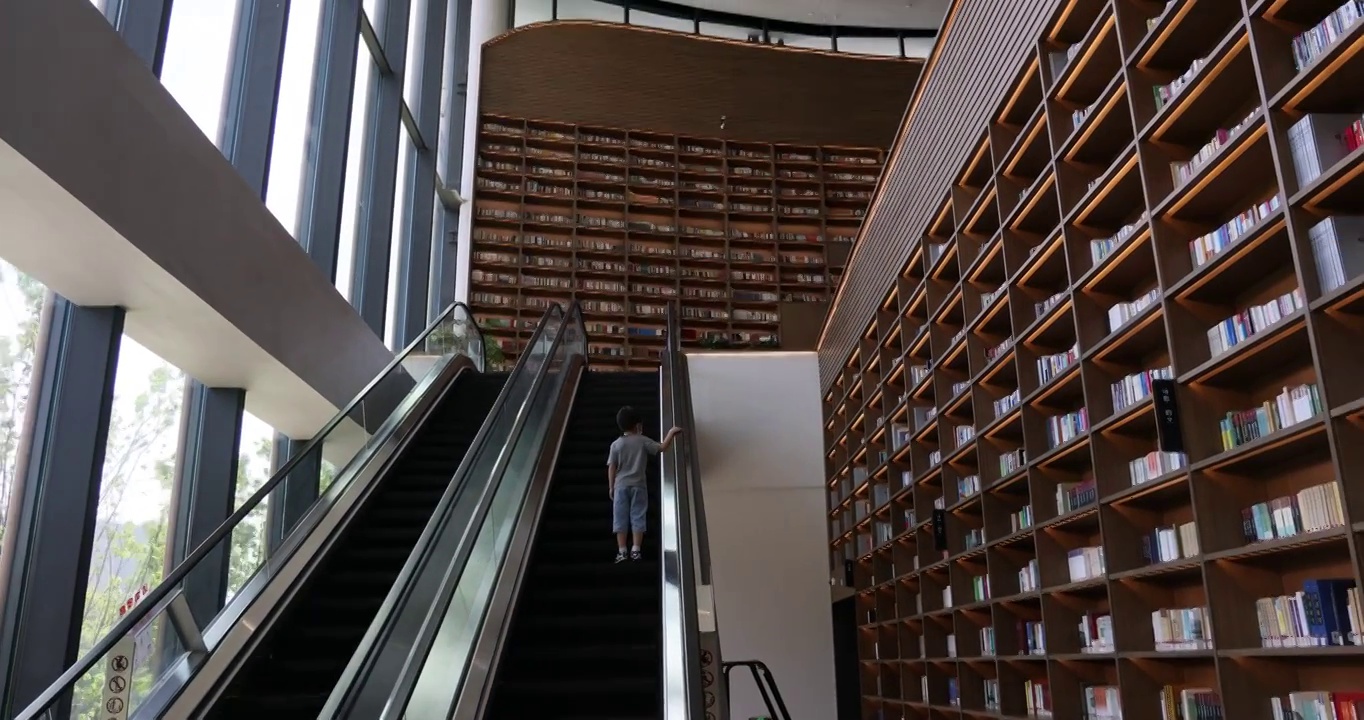 天府人文艺术图书馆里一位小男孩正在搭乘扶梯上楼视频下载