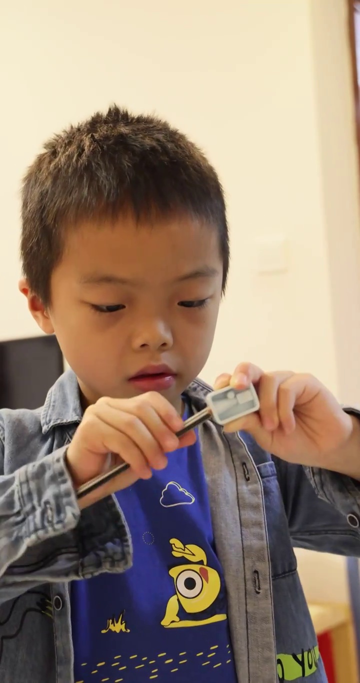 人像文具：使用削笔刀削铅笔的小男孩视频下载