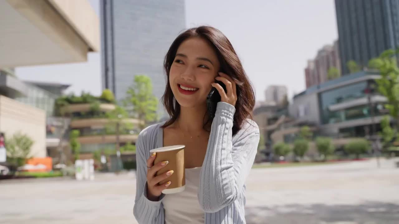 一位迷人的亚洲女孩在城市广场打电话视频素材