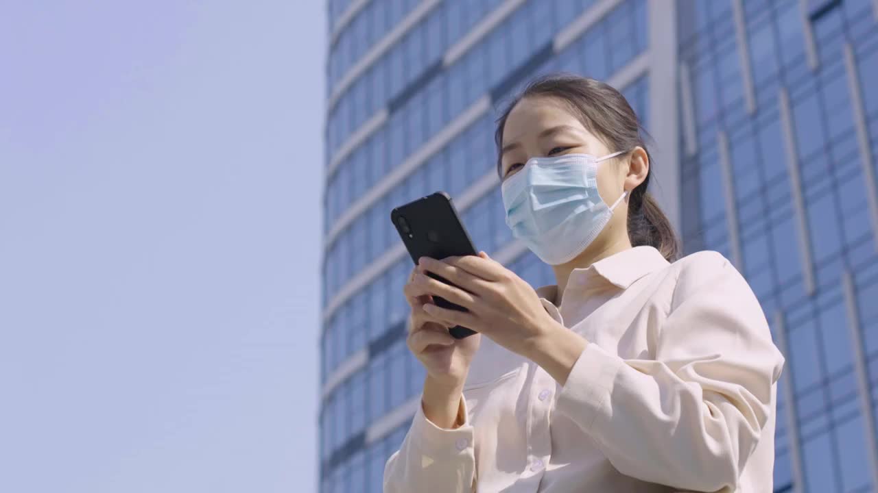 亚洲人中国女性戴口罩户外办公打电话玩手机视频素材