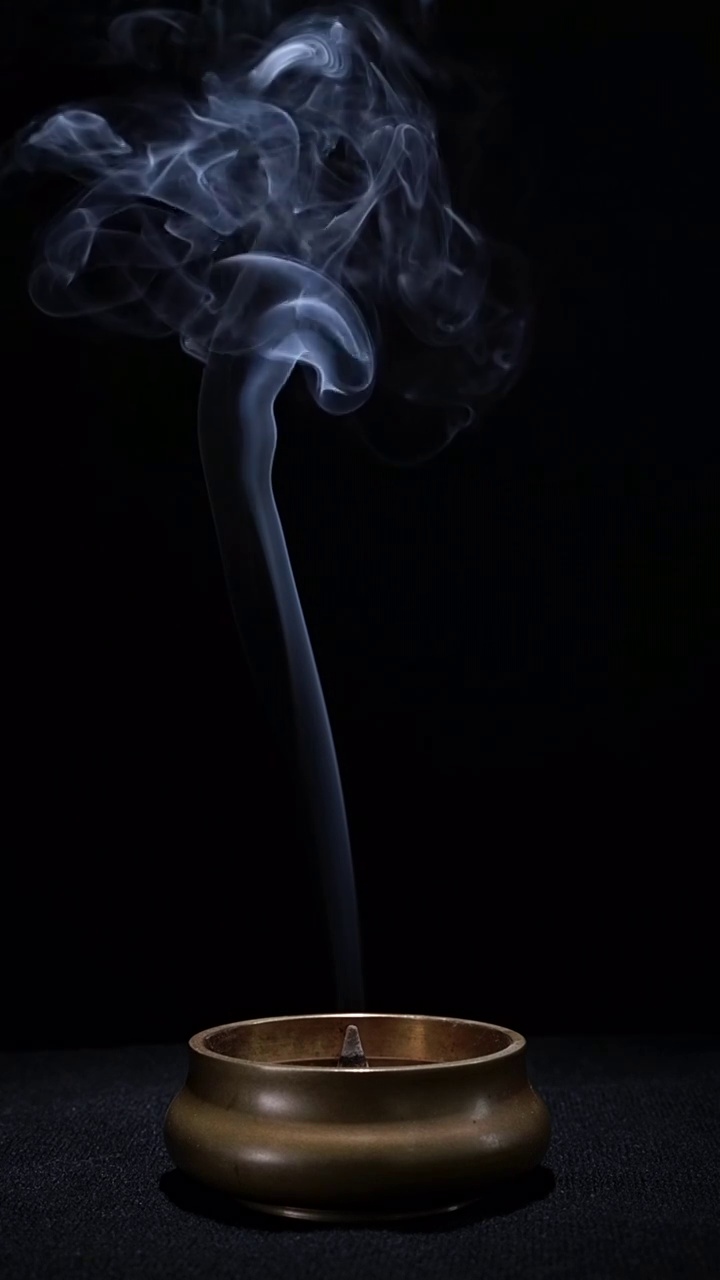 室内黑背景点燃香炉里的檀香，缓慢螺旋涡流状升起的烟雾视频下载