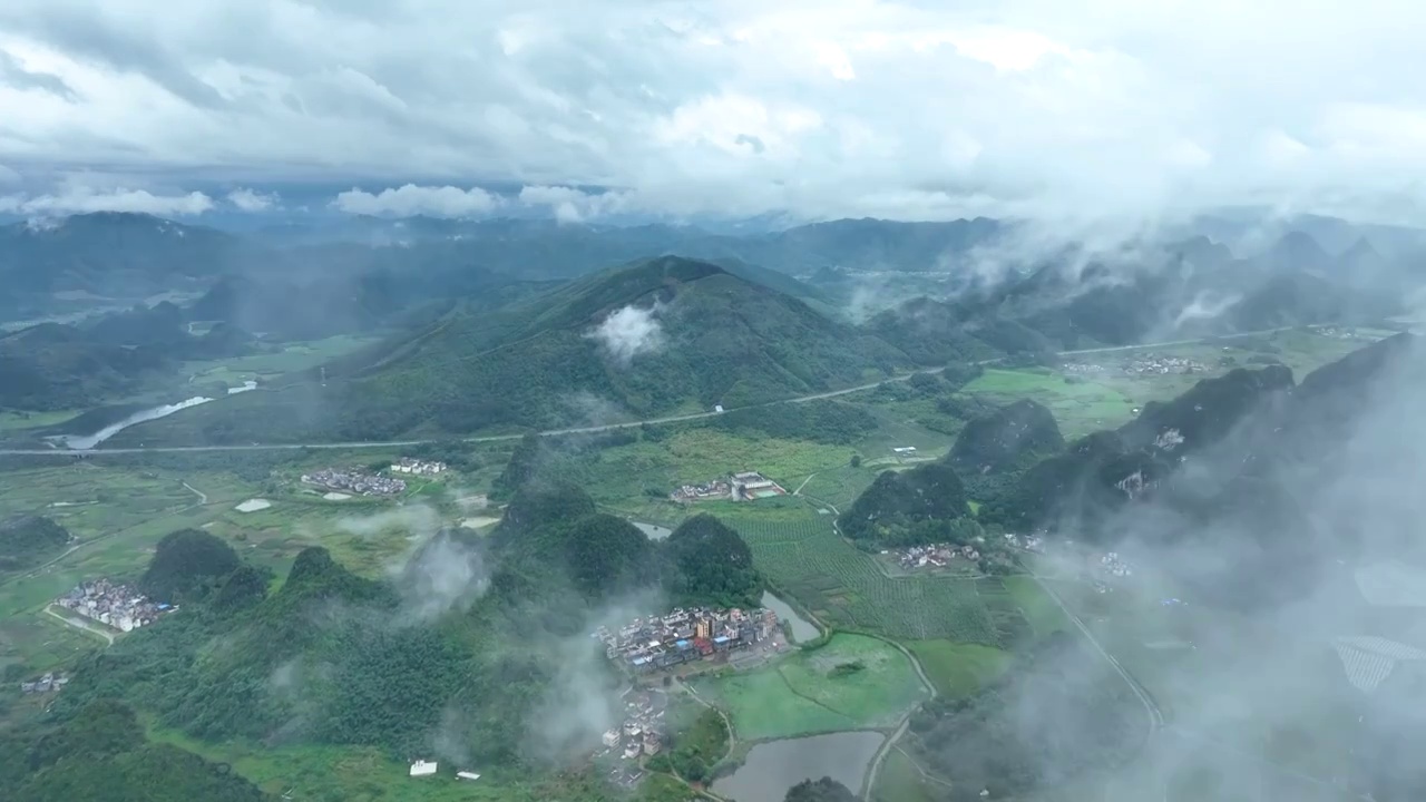 航拍夏日早晨雨后云雾缭绕的广东清远英德英西峰林与村镇田园风光视频素材