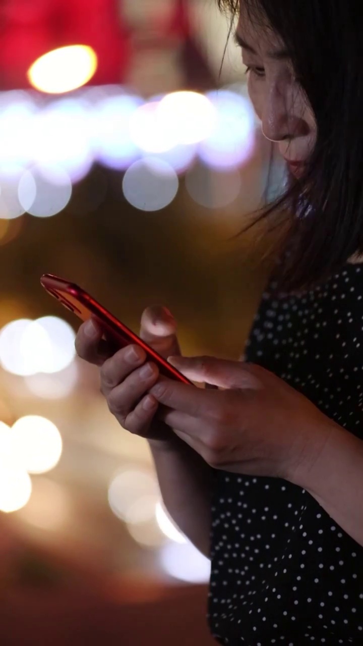 一个女人在夜晚街道上使用智能手机视频素材