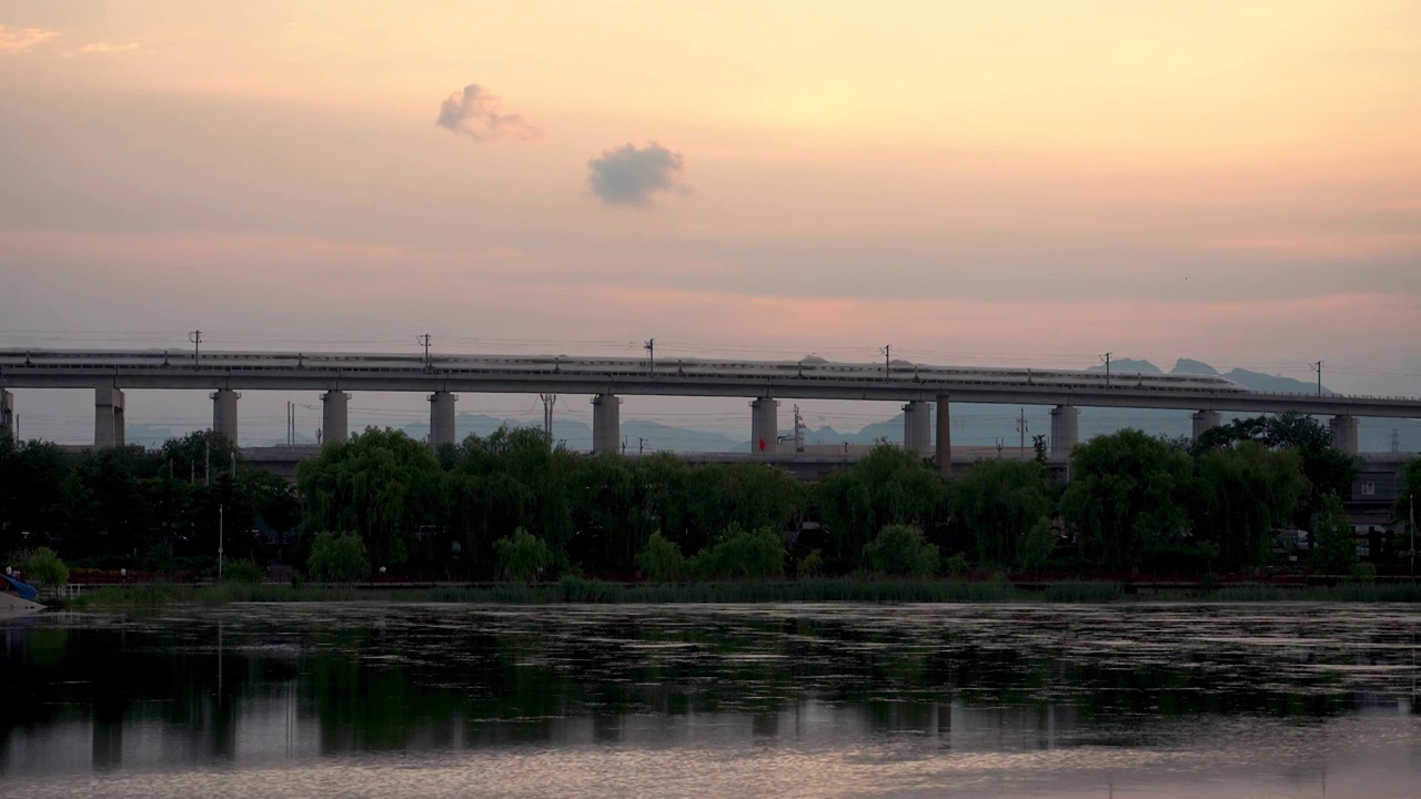 夕阳中行驶在晓月湖高架桥上的高速列车视频素材